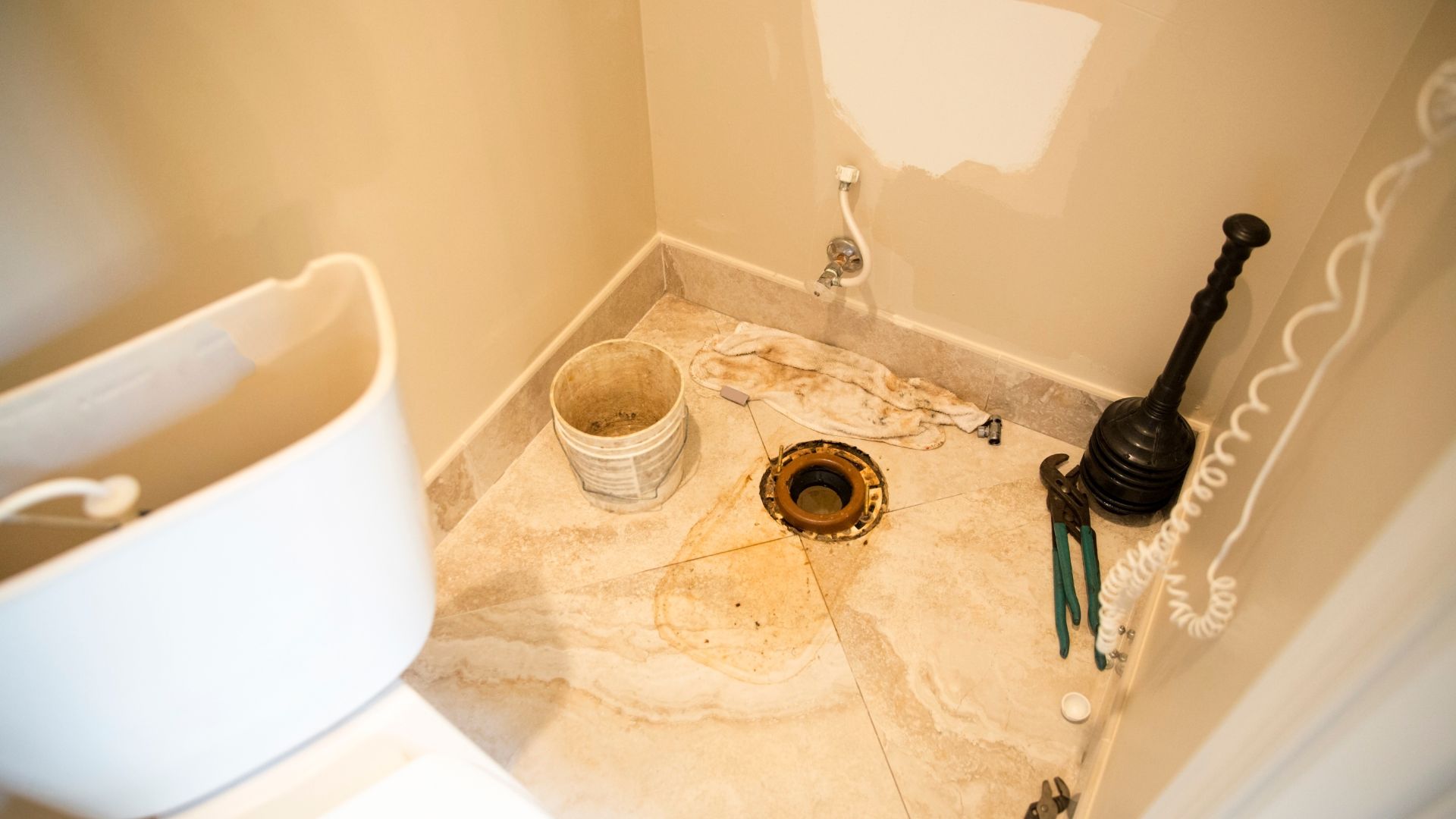 A bucket of paint sitting on the floor of a bathroom